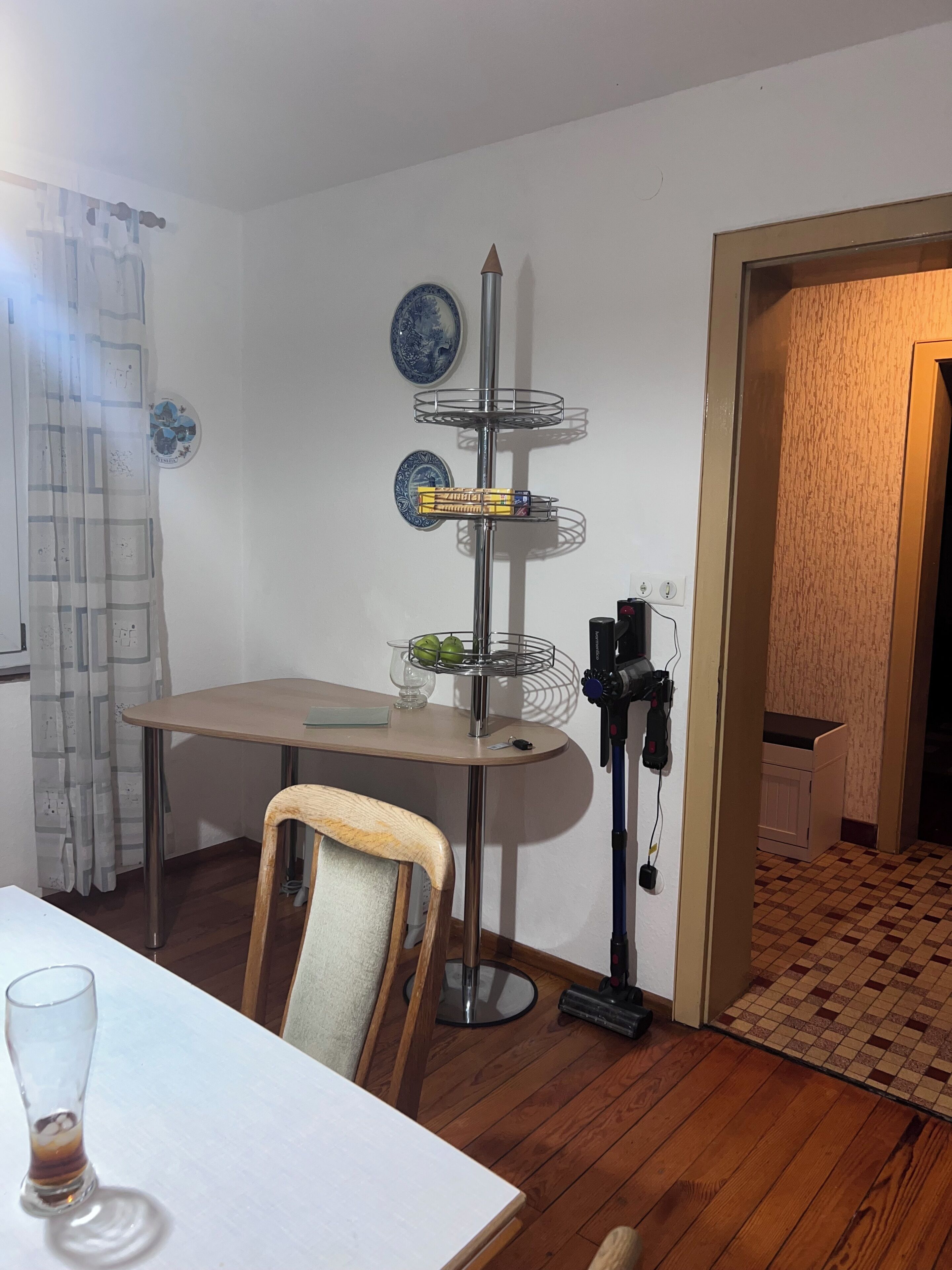 Un coin repas comprenant une table, des chaises, un présentoir décoratif et un aspirateur.