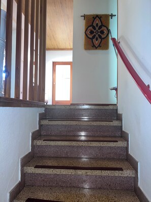 Una escalera con escalones de granito, barandilla de madera y un tapiz decorativo.