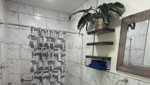 Une salle de bain avec douche, toilettes, lavabo et carrelage en marbre.