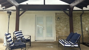 Un patio couvert comprenant deux chaises longues et une porte.