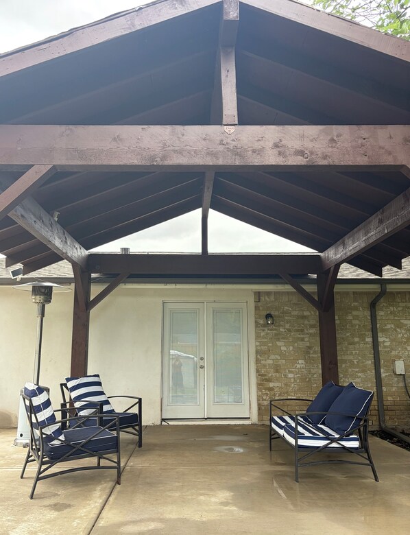 A covered patio area with two lounge chairs and a door.