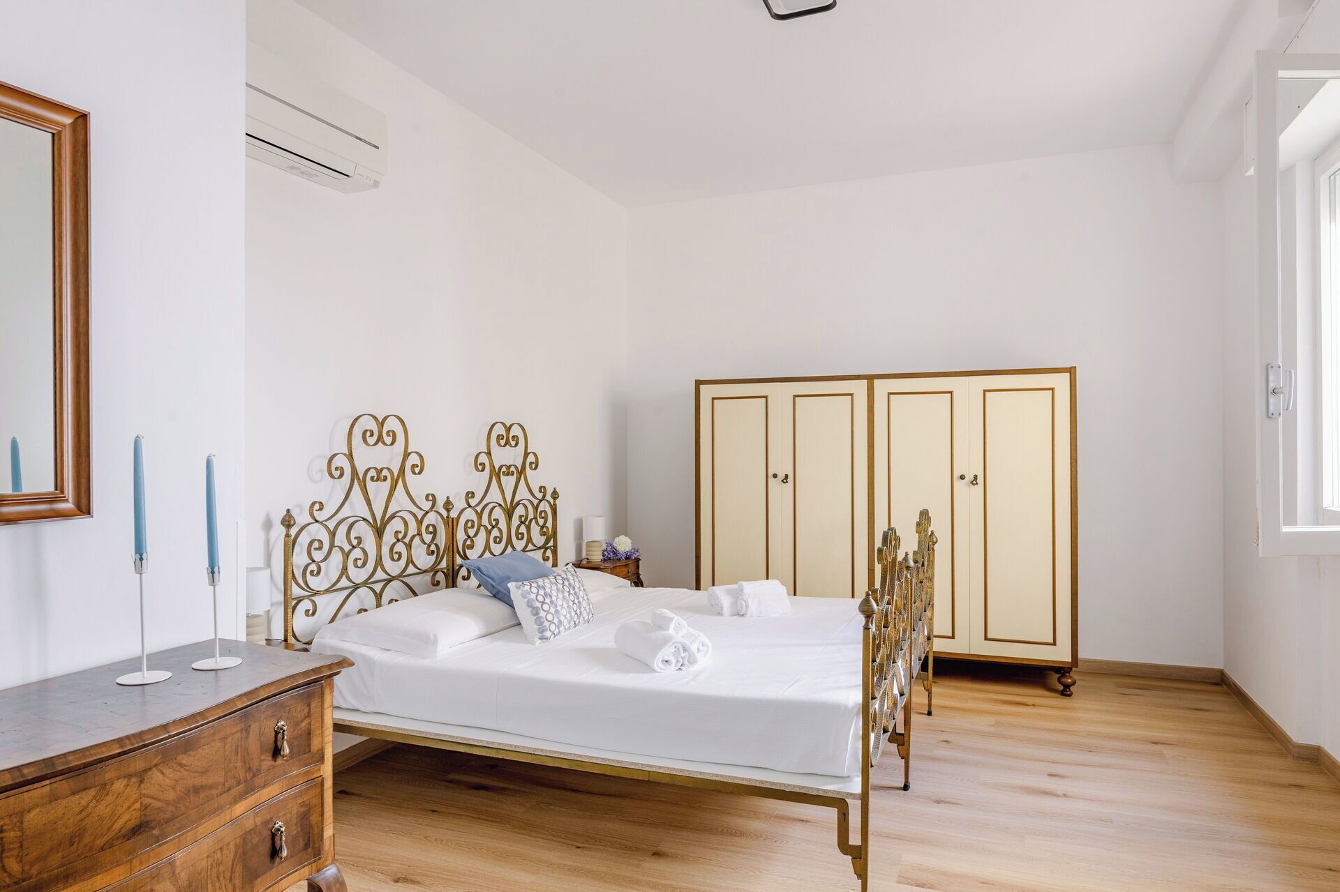 Une chambre à coucher comprenant un lit, une commode, une armoire et un miroir.