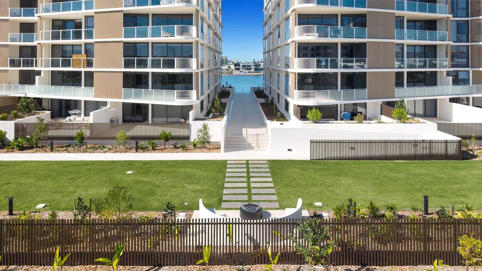 Un moderno complejo de apartamentos con un patio central, balcones y un césped bien cuidado.