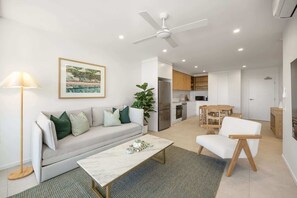 Ein modernes Wohnzimmer mit einer Couch, einem Couchtisch und einem Essbereich mit Tisch und Stühlen.