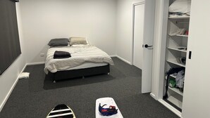 Una camera da letto con un letto, un armadio e un tavolino con scarpe.