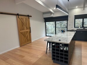 Eine moderne Küche mit einer Holztür, die sich verschieben lässt, einem großen Fenster und einem integrierten Weinkühlschrank.