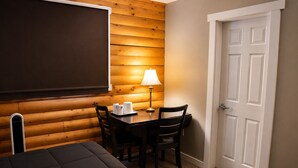 Habitación de hotel con cama, una mesa con sillas, una lámpara y una puerta.