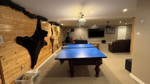 Una habitación con mesa de ping pong, cabeza de animal montada y televisor.