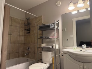 Een badkamer met een bad, toilet en een plank met handdoeken.