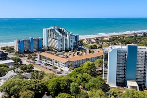 A coastal hotel with multiple buildings, a beach view, and a parking area. - NEW Remodel-Private Balcony-Elevator-Pool-King bed (Myrtle Beach)