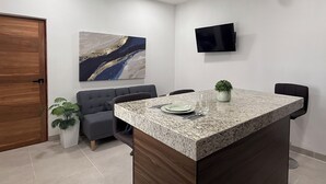 A modern office space with a granite island table, a grey sofa, a mounted TV, and a ceiling fan. - An ideal apartment for families, with an excellent location—spacious and comfortable. (La Paz)