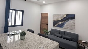 A modern room with a granite dining table, a gray sofa, a ceiling fan, a large abstract painting, and a window with curtains. - An ideal apartment for families, with an excellent location—spacious and comfortable. (La Paz)