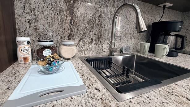 A kitchen with a granite countertop, stainless steel sink, coffee maker, and various kitchen items. - An ideal apartment for families, with an excellent location—spacious and comfortable. (La Paz)
