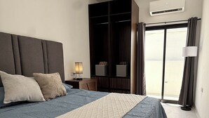 A bedroom with a bed, a ceiling fan, a wardrobe, an air conditioning unit, and a view through a sliding door. - An ideal apartment for families, with an excellent location—spacious and comfortable. (La Paz)