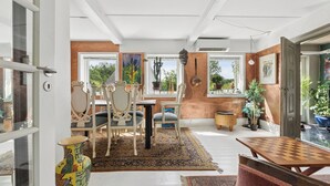 Una habitación con una mesa de comedor, sillas, un florero y un tablero de ajedrez.