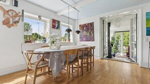 Un comedor con una mesa y sillas de madera, un jarrón con flores y vistas al exterior.