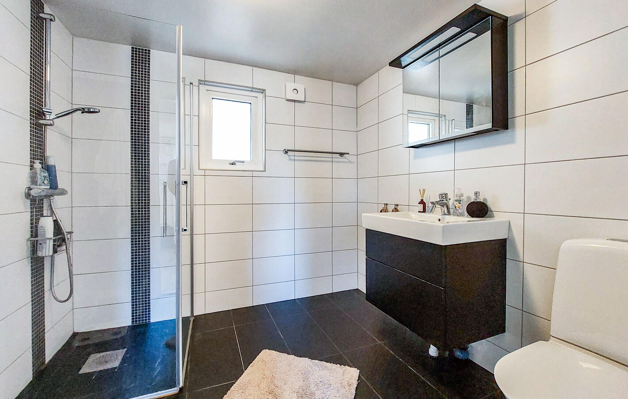 A modern bathroom with a shower, a sink, and a toilet.