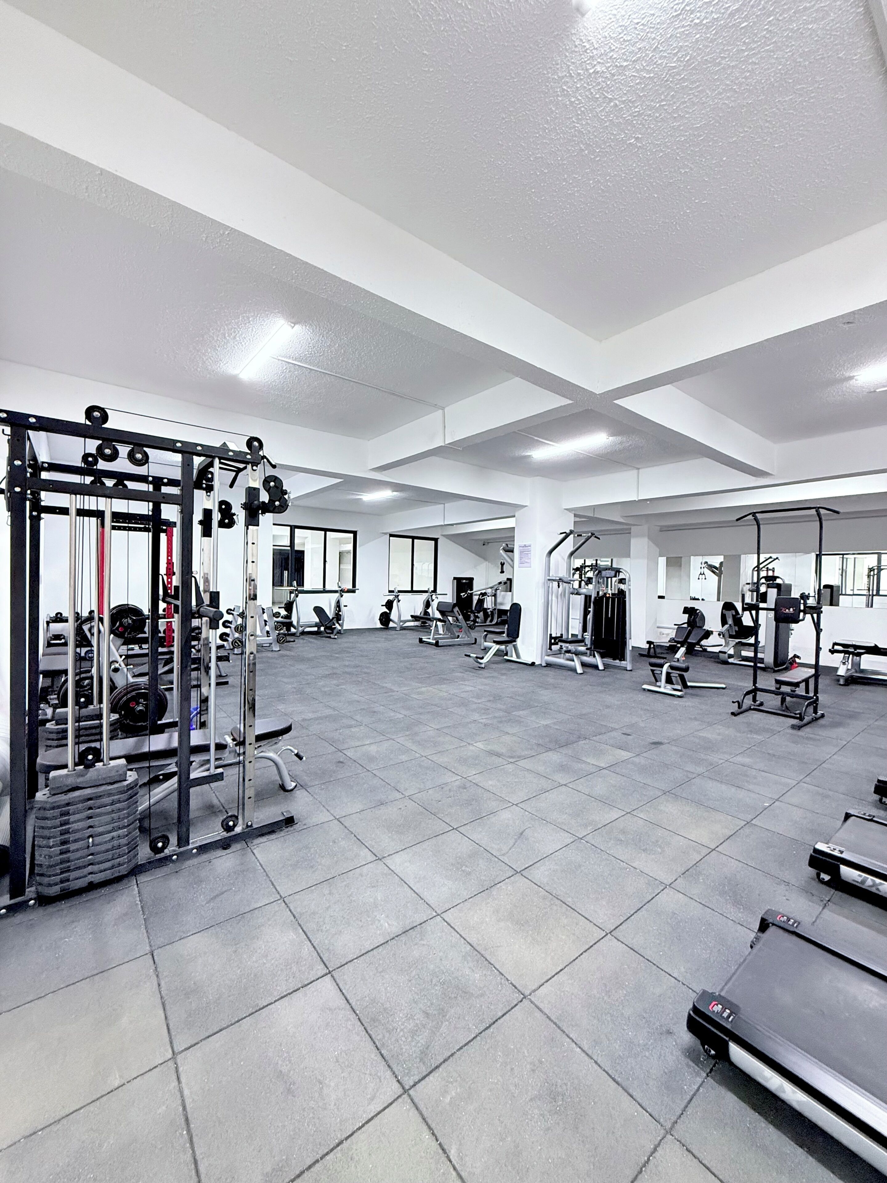 A spacious gym with various exercise equipment, including weight machines and treadmills.