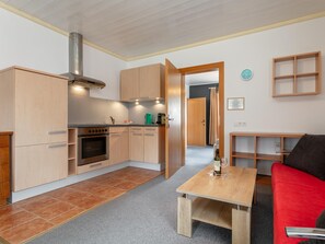 A compact kitchen with wooden cabinets, a built-in oven, and a stainless steel range hood.