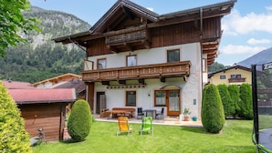 Un chalet à deux étages doté d’un balcon, d  ’une terrasse en bois et d’une pelouse bien entretenue.