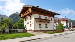 Un bâtiment à deux étages doté d’un balcon, avec une chaîne de montagnes en arrière-plan et un ciel dégagé.
