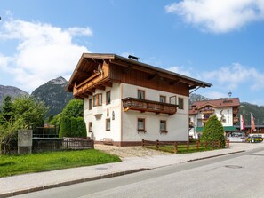 A two-story building with a balcony, a mountain backdrop, and a clear sky.