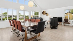 A spacious dining area with a large table and multiple chairs, large windows, and a modern interior design. - Scenic holiday home close to the water (Brenderup)