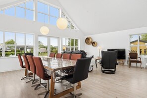 A spacious dining area with a large table and multiple chairs, large windows, and a modern interior design. - Scenic holiday home close to the water (Brenderup)