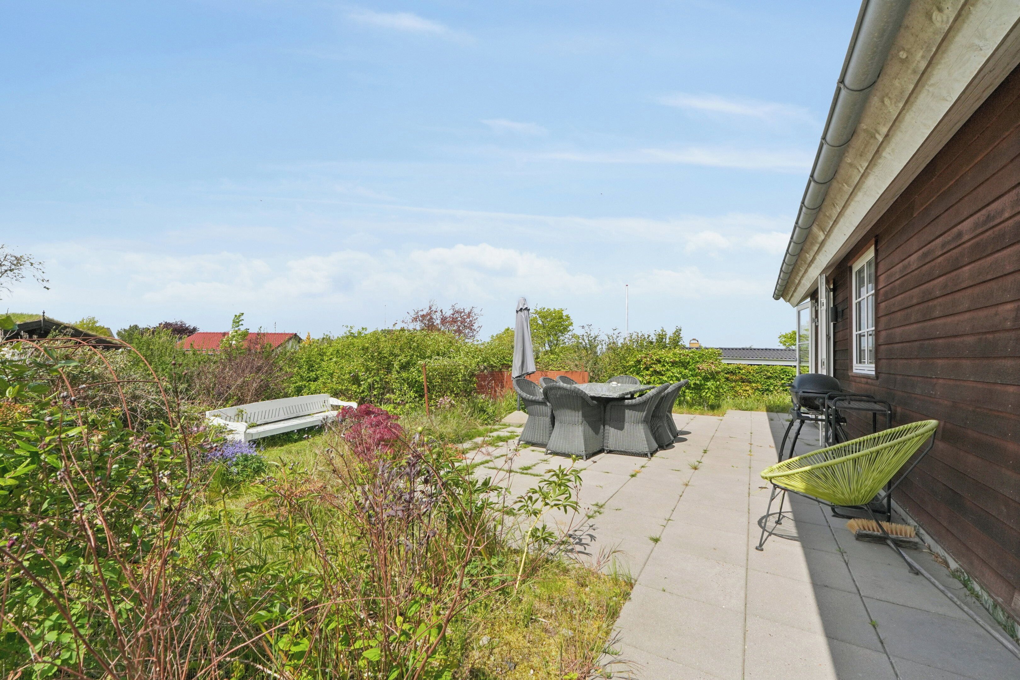 A patio with outdoor furniture, a wooden house, and surrounding greenery.