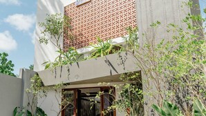 Ein modernes Gebäude mit einer geometrischen Fassade, einem Glastürbereich und einem gepflegten Garten.