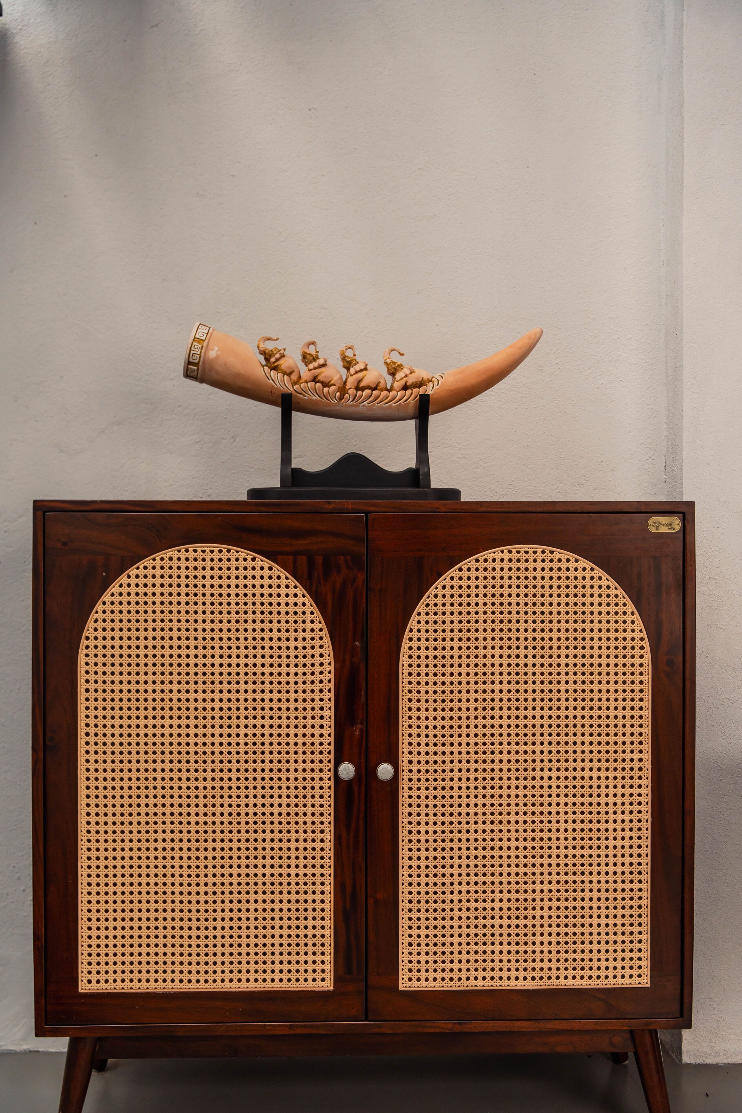 A wooden cabinet with two large arched doors and a decorative item on top.