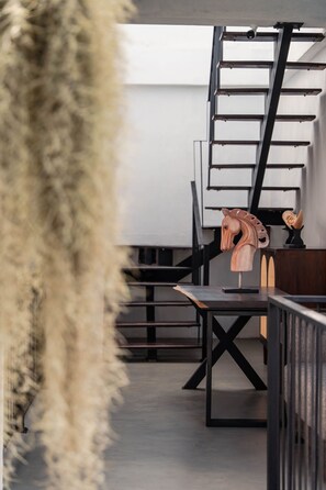 Un escalier avec une rampe en métal, une sculpture équestre en bois et une table dont le piétement est noir.