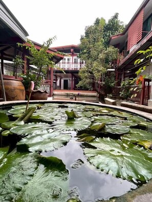 A courtyard with a pond, potted plants, and a building with a balcony. - Casa Scarlet (Krung Thep Maha Nakhon)