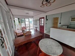 A spacious room with a wooden dining table, a marble table, and a red door. - Casa Scarlet (Krung Thep Maha Nakhon)