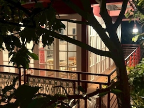 A building with a balcony, a staircase, and a tree in the foreground.