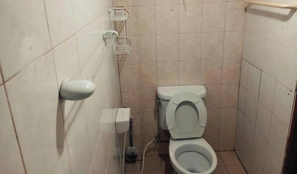 A small, tiled bathroom with a toilet, a hand dryer, and a trash bin. - Casa Scarlet (Bangkok)