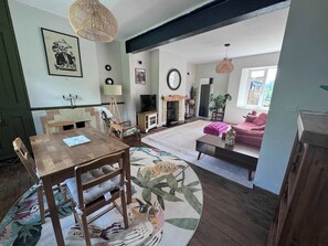 Ein Wohnzimmer mit Holzesstisch, Stühlen, einer Couch, einem Kamin und einem großen Fenster.