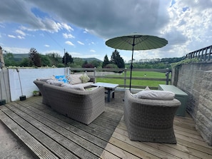 Una terraza con mobiliario de mimbre, una mesa y una sombrilla.