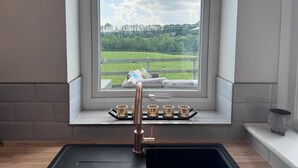 Una cocina con vista a un campo verde y árboles.