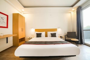 Ein Hotelzimmer mit einem großen Bett, einem Holzschrank, einem Schreibtisch mit Stuhl und einem fenster mit Vorhängen.