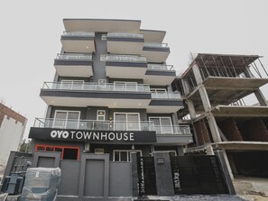 Ein mehrstöckiges Gebäude mit Balkonen, einem Schild mit der Aufschrift 'YOYOTOWNHOUSE' und einem verschlossenen Eingang.