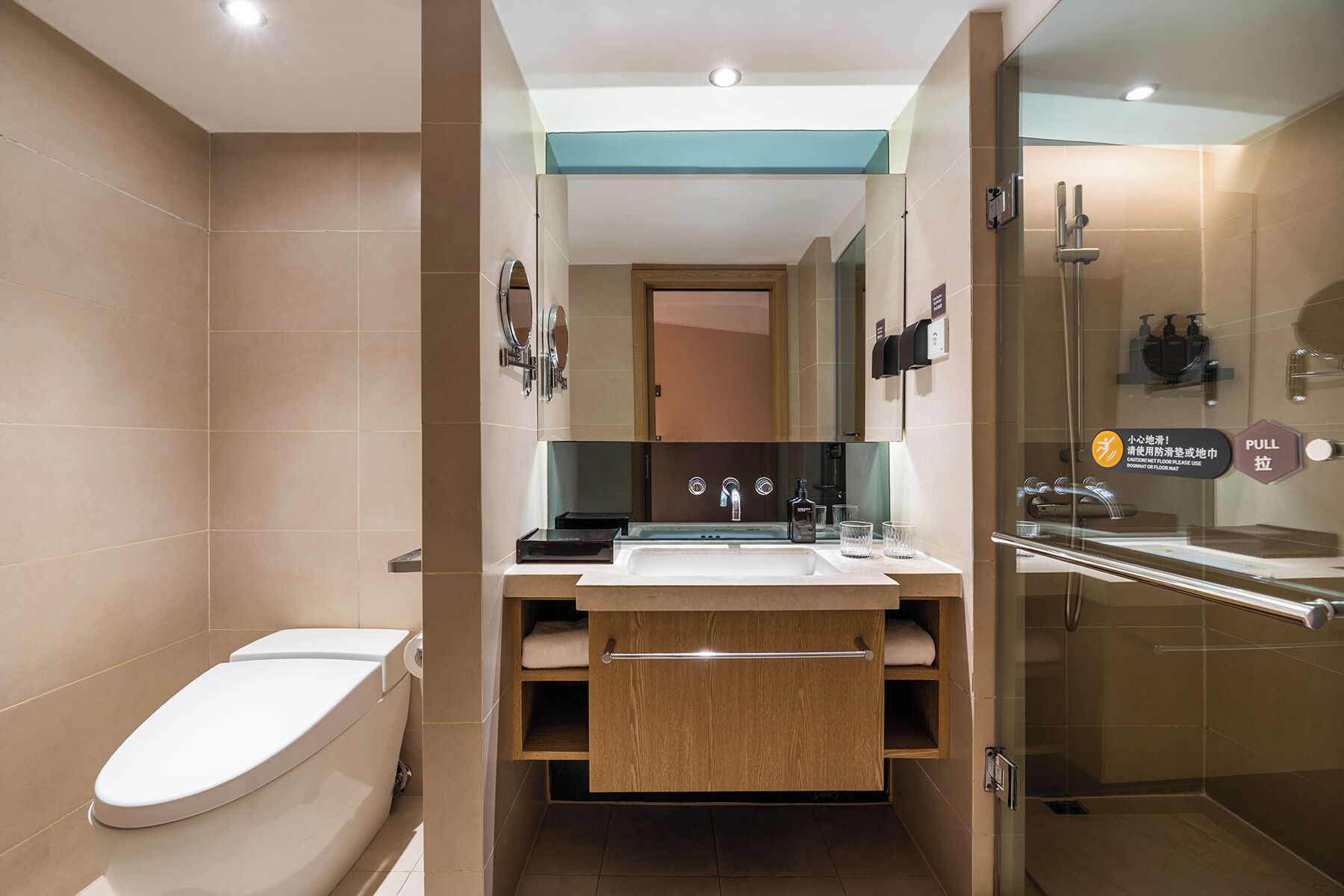 A modern bathroom with a toilet, sink, mirror, and shower.