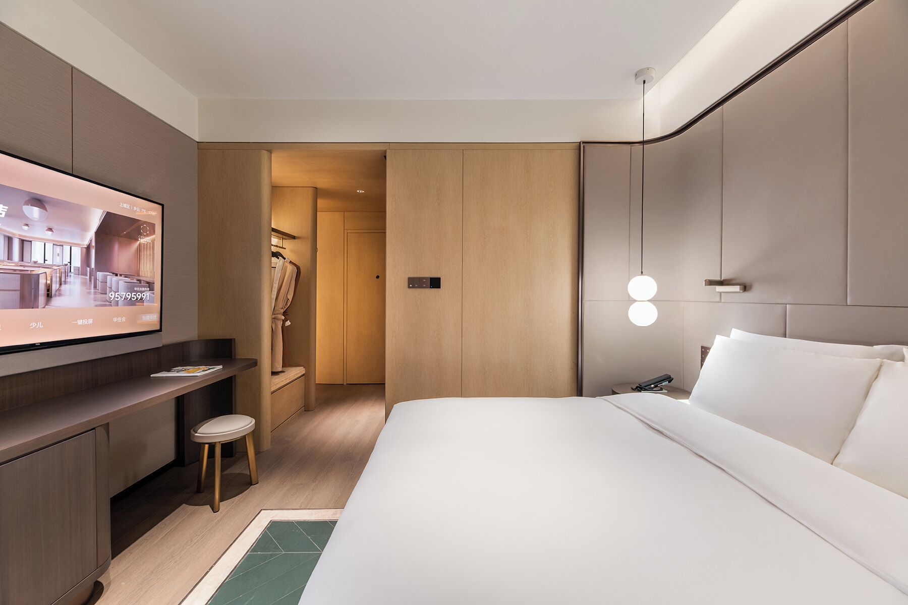 Una habitación de hotel moderna con cama, escritorio, televisor y vestidor.