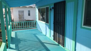Un portico riparato con ringhiera, una porta con cancello metallico e una finestra.
