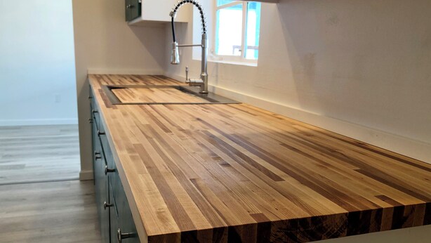 Cucina con piano di lavoro in legno, rubinetto in acciaio inossidabile e finestra vista panoramica.