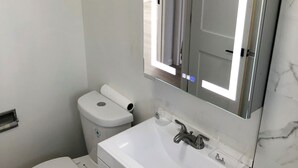 Un bagno con il water, un lavandino e uno specchio.