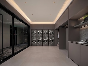 A modern laundry room with multiple washing machines, a glass wall, and a minimalist design. - Intercity Hotel Qingdao Downtown (Qing Dao Shi)