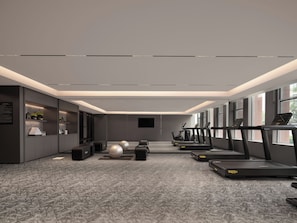 Une salle de sport moderne équipée de tapis de course, de ballons d’exercice et dotée d’un sol recouvert d’un tapis gris.