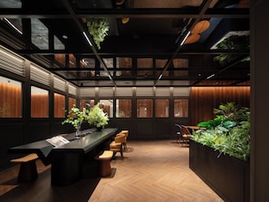 Une salle de conférence moderne, dotée d’une longue table, de chaises et de plantes en pot.