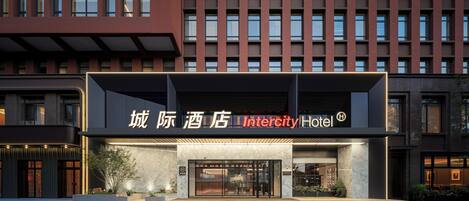 Un hôtel moderne doté d’une entrée imposante, de grandes fenêtres et d’une enseigne bien visible indiquant le nom « Intercity Hotel ».